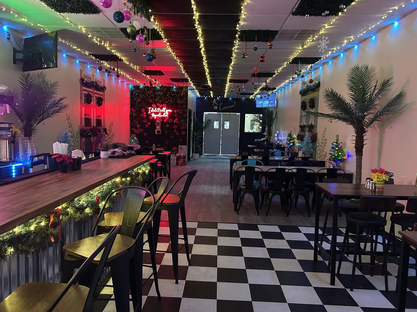 Our dining room: a black and white checkerboard floor, painted Havana building fronts along the walls, palms and string lights